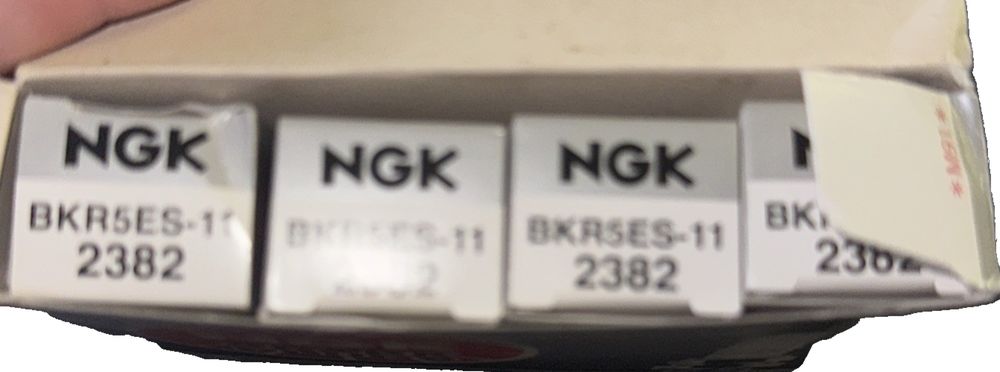 NGK Spark Plugs BKR5ES-11 4 Pack – a person holding a pair of white and black ink